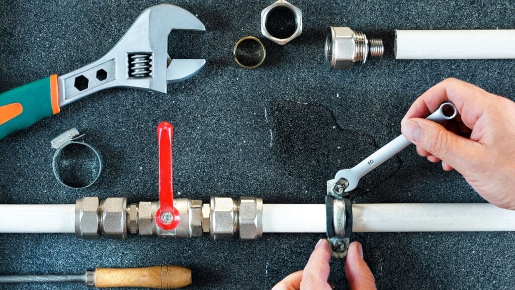 Plumber repairing a pipe valve with an adjustable wrench in Crestview