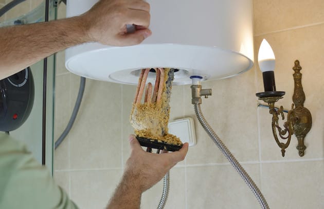 Technician removing mineral buildup from a water heater in Crestview