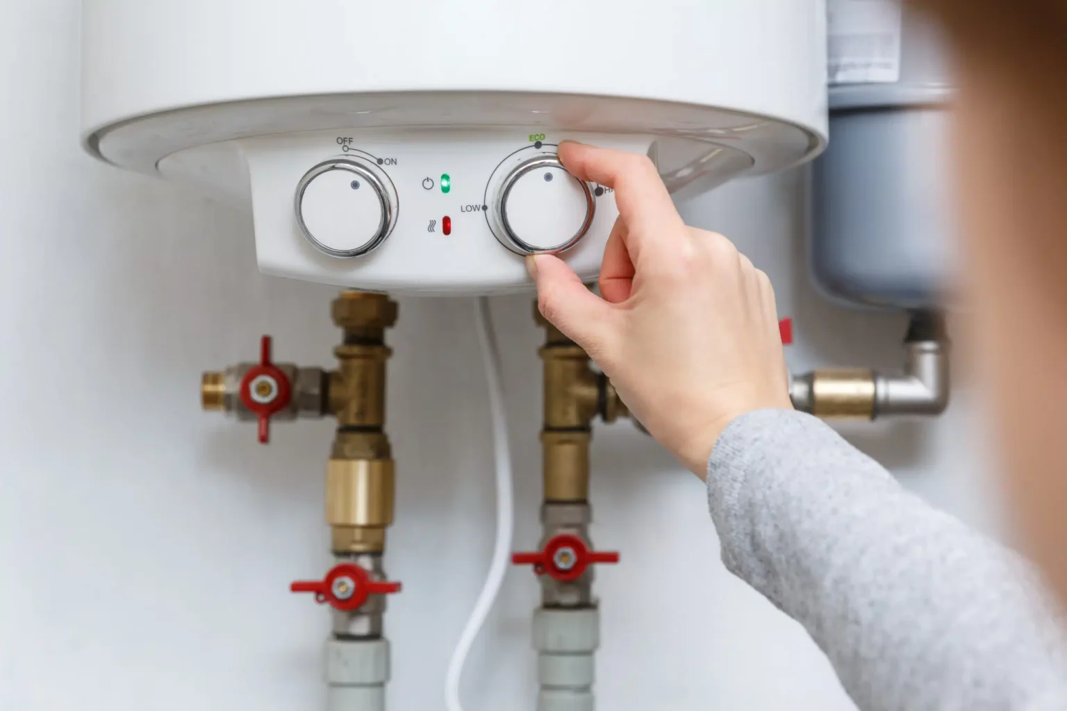 Homeowner adjusting the temperature controls on a water heater in Crestview